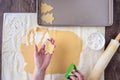 WomanÃ¢â¬â¢s hands cutting out Christmas tree sugar cookies, pastry cloth, cookie sheet Royalty Free Stock Photo